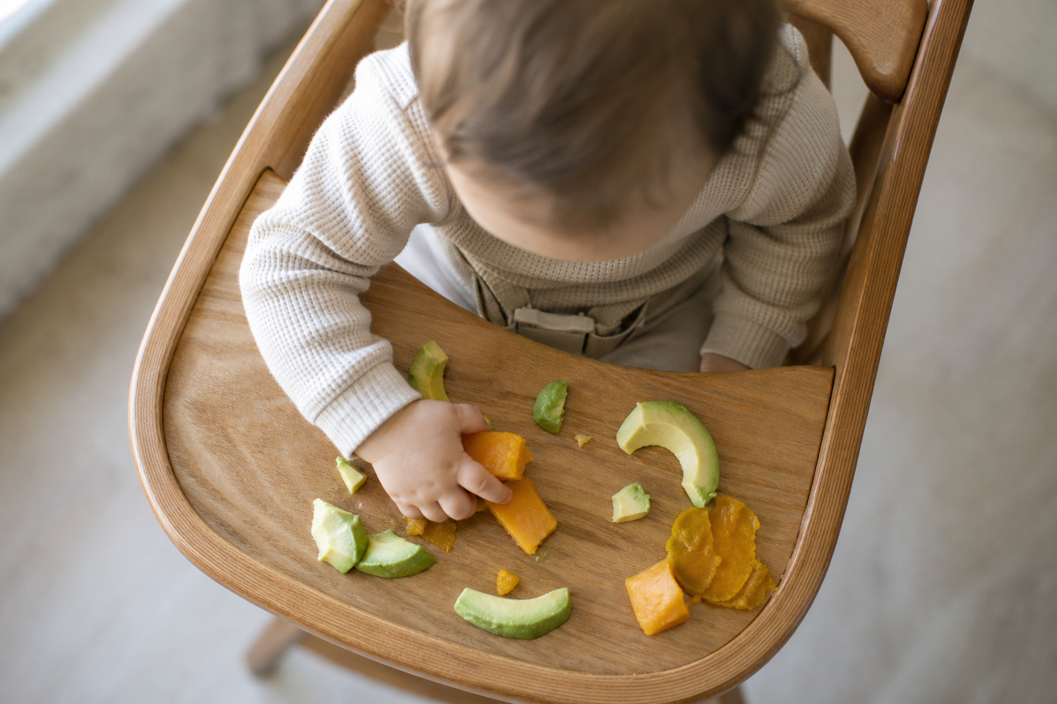 baby in high chair eating pieces of the healthiest food for a baby
